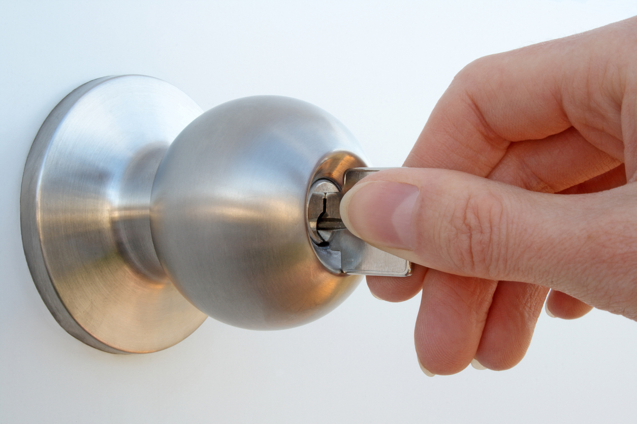 Woman's hand unlocking the door with a key.